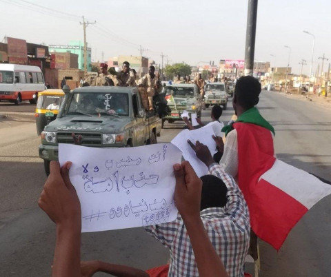 The strike on 28–29 May 2019 – Revolutionaries in the street lift strike signs before Rapid Support Forces cars in Khartoum, text on paper: “Are you on strike or are you Ummah #CivilianRule” (Ummah Party, one of the biggest parties, which announced its refusal to strike)