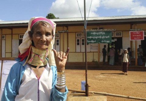 A Kayan woman, from one of Myanamr's ethnic minority groups, shows her ink-stained finger after she voted, in front of a polling station in Panpet village